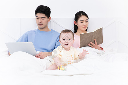 爸爸和婴儿爸爸看电脑妈妈看书婴儿自己玩闹背景