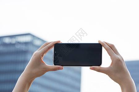 女性拿手机拍远处建筑特写图片
