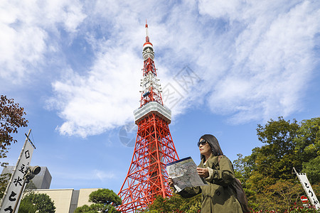 东京地图站在东京塔前看旅游地图的旅行者背景