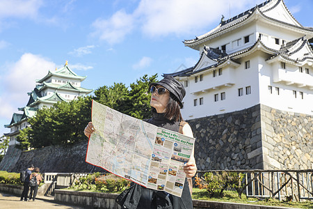 在名古屋城前看旅游地图的旅行者图片