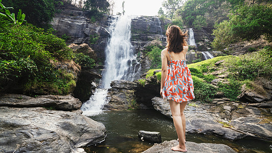 泰国旅行面对瀑布的长裙少女背影图片