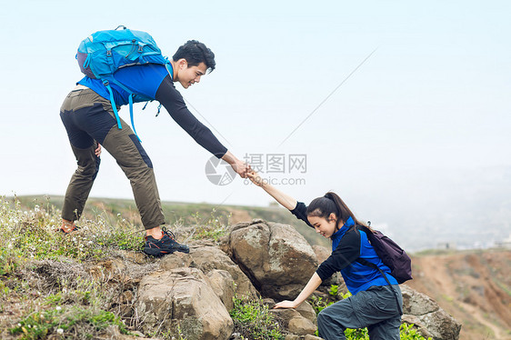 郊外携手爬山的男女青年图片