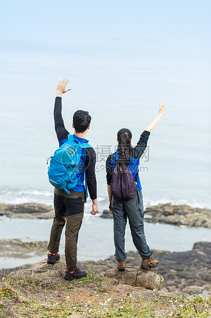 野外海边背包男女挥手图片