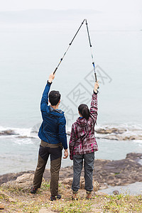 野外海边举登山杖的情侣图片