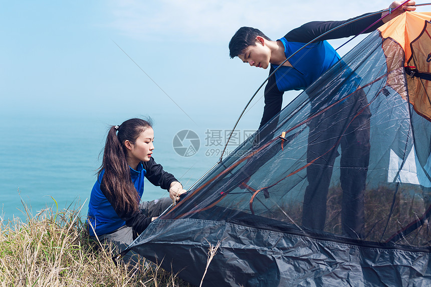 野外海边一起搭帐篷的男女图片