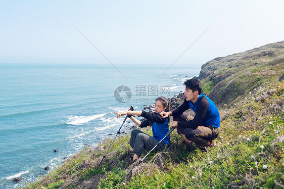 坐在海边山坡上远望男女图片