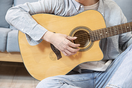 在家练习吉他的青年男性图片