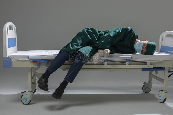 男性手术服医生瘫倒在病床上图片