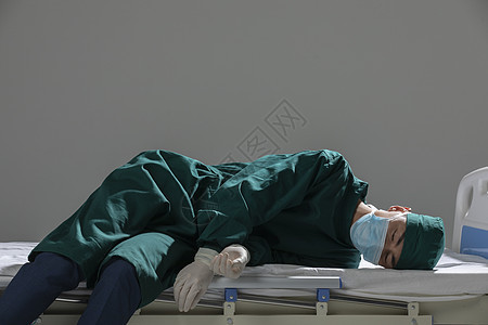 男性手术服医生瘫倒在病床上图片