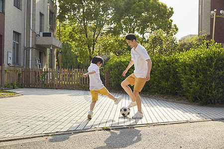 儿童玩耍年轻爸爸和儿子一起踢足球背景