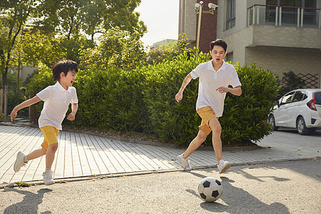 年轻爸爸和儿子一起踢足球图片