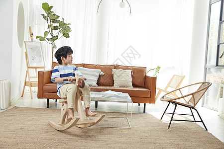 小男孩在客厅玩木马玩具高清图片