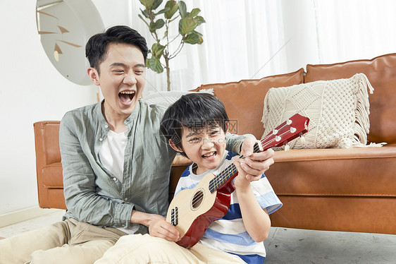 父亲和孩子在家一起玩乐器图片