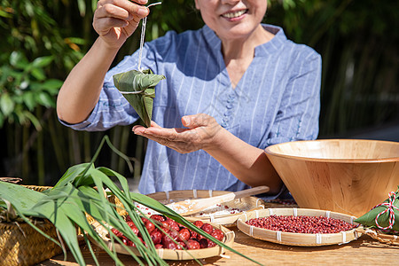 端午节奶奶户外包粽子特写图片