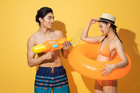 夏日泳装情侣拿着水枪和游泳圈图片