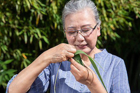 端午节户外奶奶包粽子特写图片