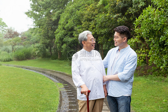 儿子搀扶父亲拄拐逛公园图片