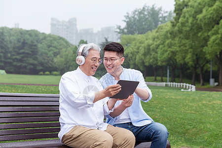 中老年父子公园长椅上听音乐图片