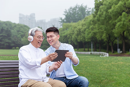 中老年父子公园长椅上听音乐图片