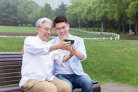 中老年父子公园长椅上手机自拍图片