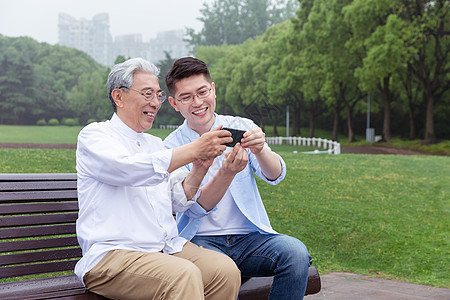 重阳节手机海报中老年父子公园长椅上手机自拍背景