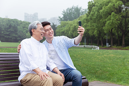 重阳节手机海报中老年父子公园长椅上手机自拍背景
