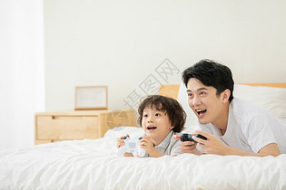 父子居家床上玩电子游戏图片