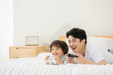 父子躺床上玩电子游戏图片