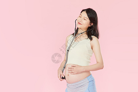 怀孕的妈妈孕妇用听诊器听自己胎动背景