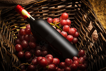 葡萄酒瓶放在藤编篮子里的红酒瓶和酿酒葡萄背景
