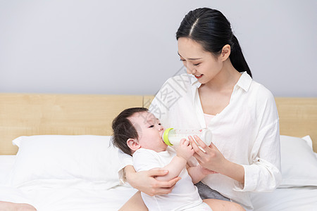 漂亮妈妈喂奶瓶妈妈抱着婴儿喂奶背景
