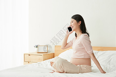 母亲打电话孕妇坐床上打电话背景