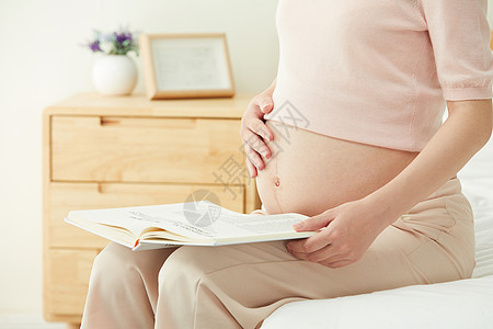 母亲节孕妇坐在床边阅读背景
