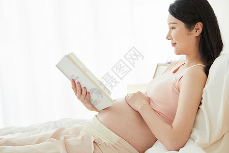 母亲节孕妇躺在床上看书背景