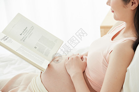 孕妇躺在床上看书背景图片