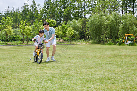 爸爸陪伴小男孩骑自行车图片