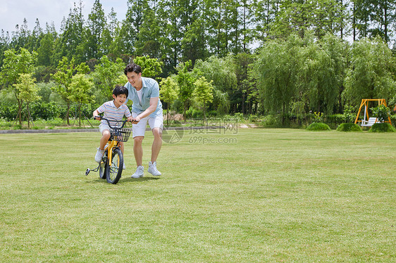 爸爸陪伴小男孩骑自行车图片