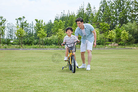 爸爸陪伴小男孩骑自行车图片