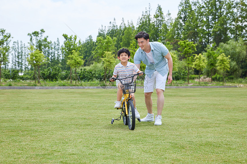 爸爸陪伴小男孩骑自行车图片