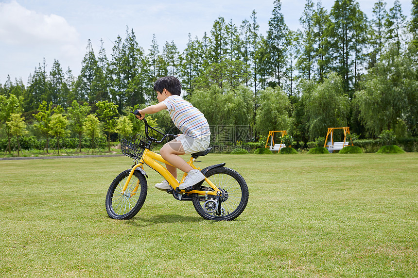 小男孩草坪上骑单车图片