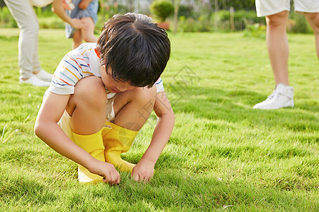 小男孩蹲在草坪上低头生闷气图片