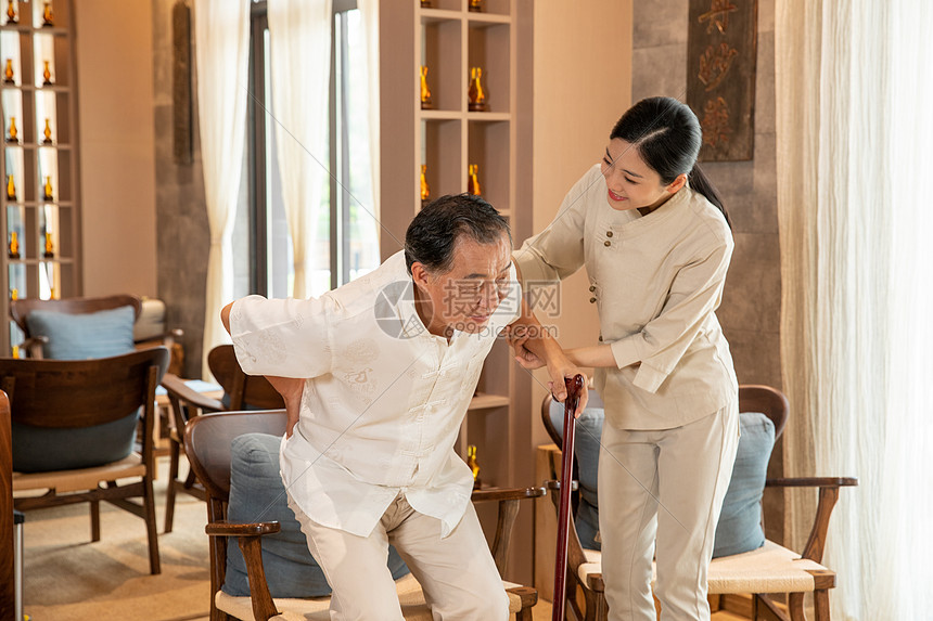 中医养生馆员工搀扶腰痛老人图片