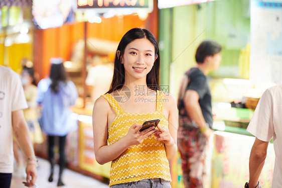 青年美女逛夜市玩手机图片