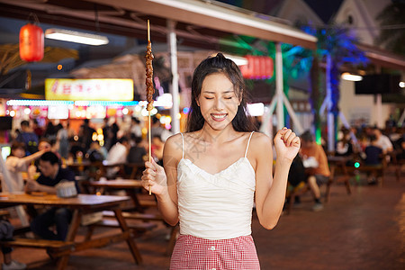 美女逛夜市品尝特色羊肉串背景图片