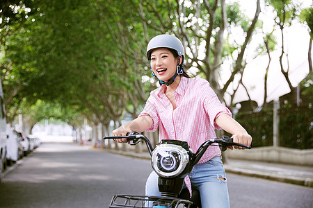 青年女性户外骑电动车背景图片