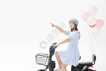 青年女性戴头盔骑电动车背景图片