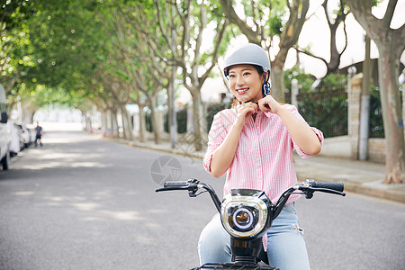 美女户外骑电动车戴头盔背景图片