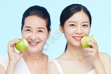 年轻美女和中年女士一起咬苹果动作高清图片