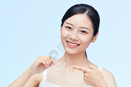 健康微笑年轻女性手拿牙套展示背景
