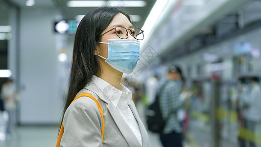疫情期间地铁戴眼镜的上班族女生在耐心等待地铁背景图片